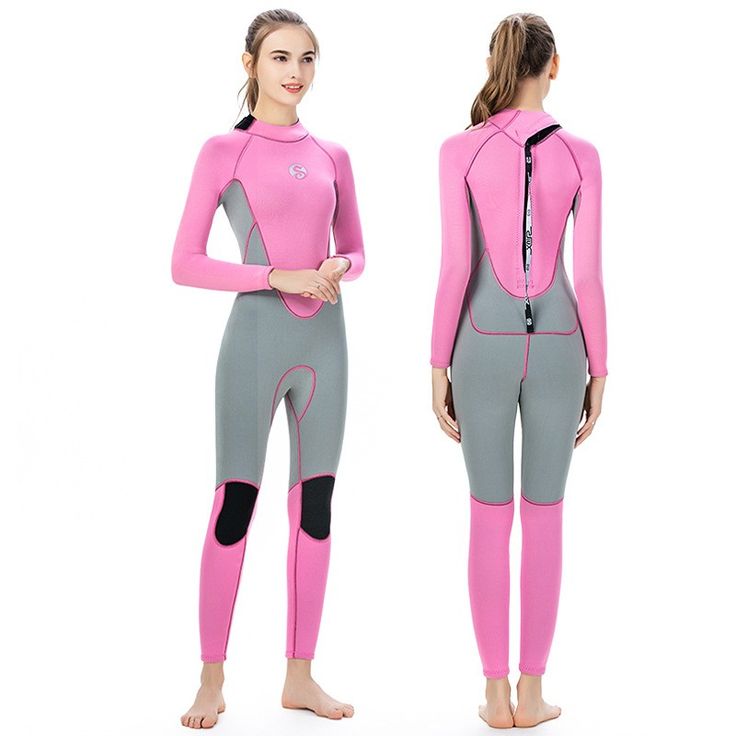 a woman in a pink and grey wetsuit standing next to another woman with her arms crossed