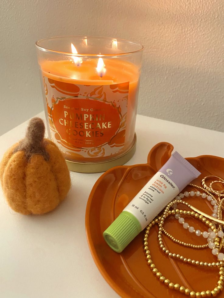 a candle and some beads are on a plate next to a small pumpkin shaped object