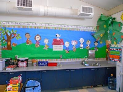 a classroom with blue cabinets and a mural on the wall above it's sink