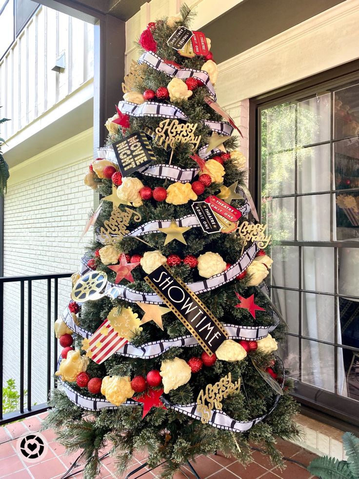 a decorated christmas tree on the front porch with red, white and blue ribbons around it