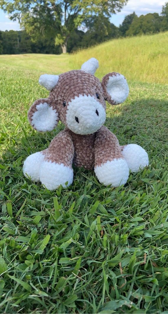 a brown and white stuffed animal sitting in the grass