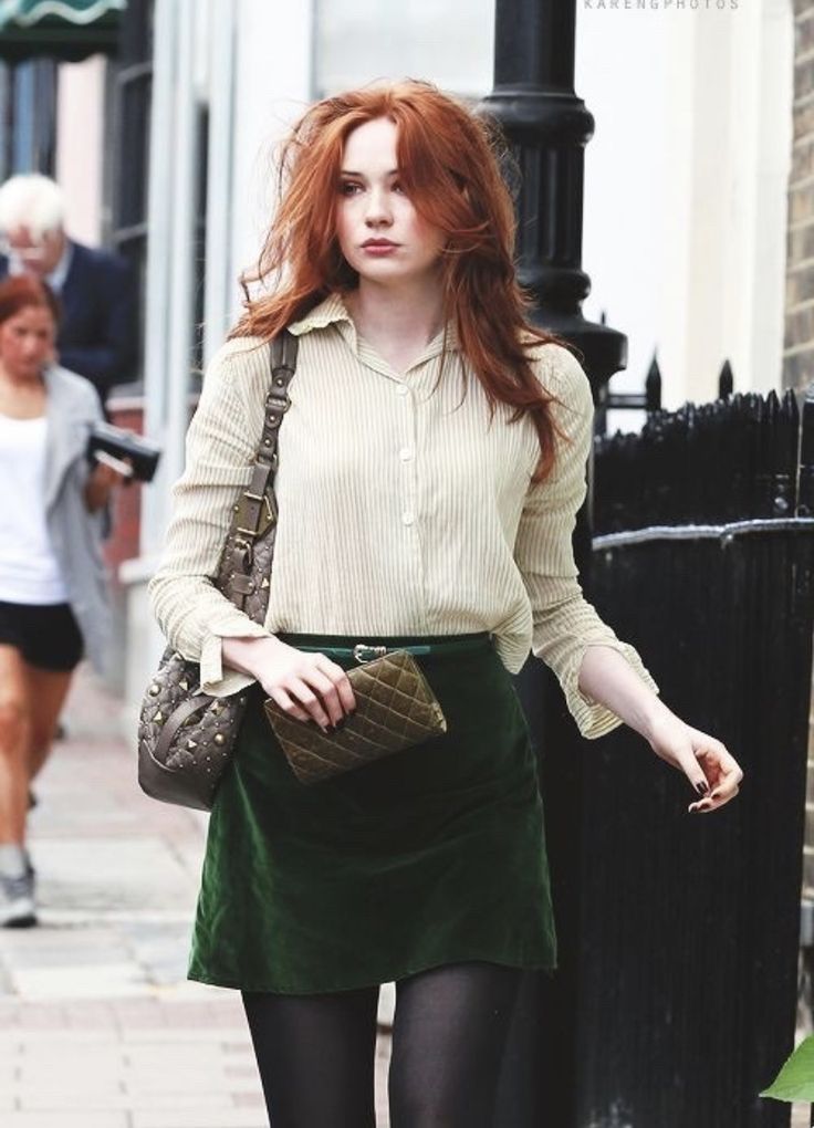 a woman with red hair is walking down the street while wearing tights and heels