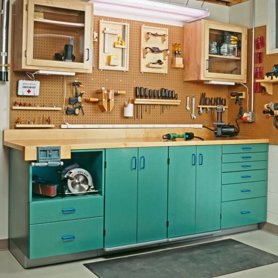 a workbench with lots of tools on the wall and cupboards above it