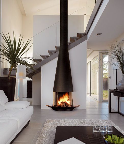 a living room filled with furniture and a fire place next to a stair case on the wall