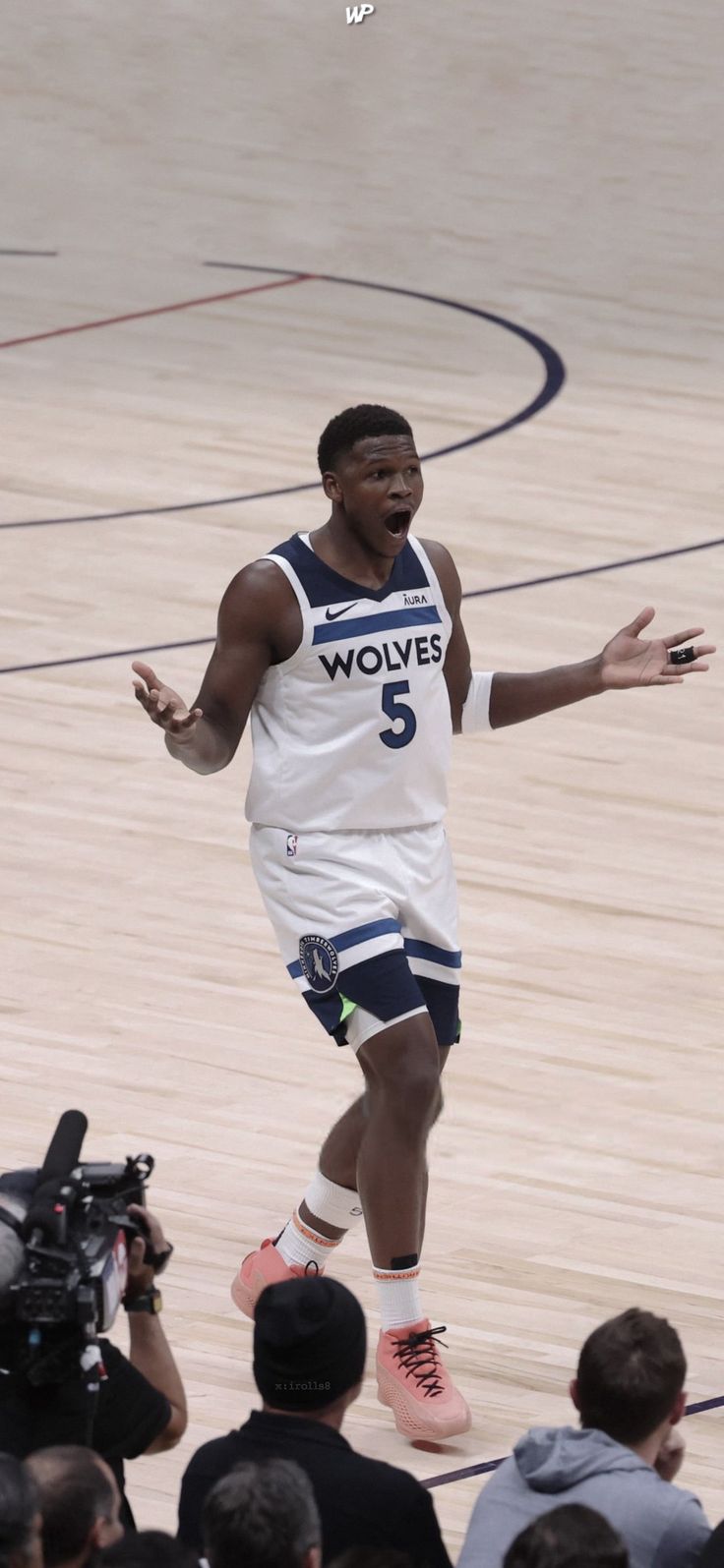 a basketball player is in mid air with his arms out to catch the ball while people watch