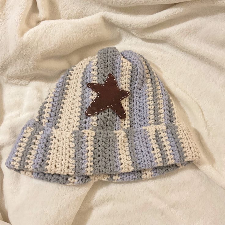 a crocheted hat with a brown star on the top is laying on a bed