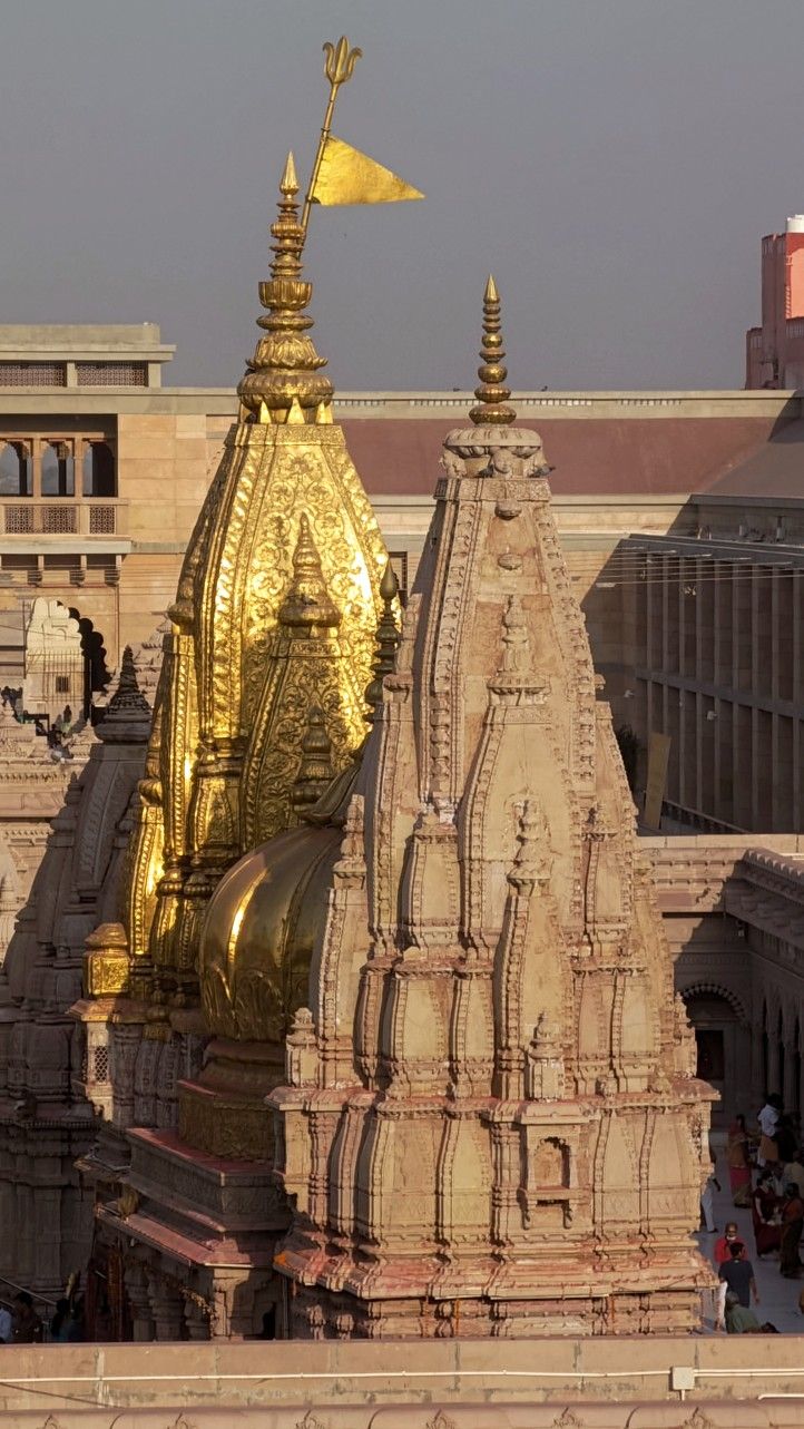 the top of an ornate building with golden spires and flags flying in the wind