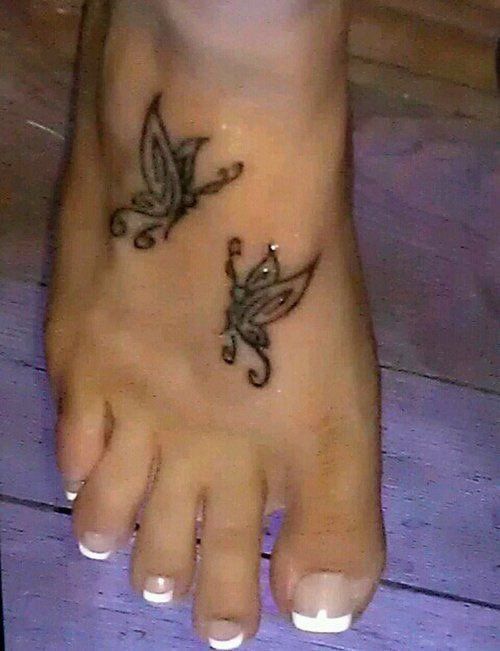 a woman's foot with a butterfly tattoo on the top and bottom of it