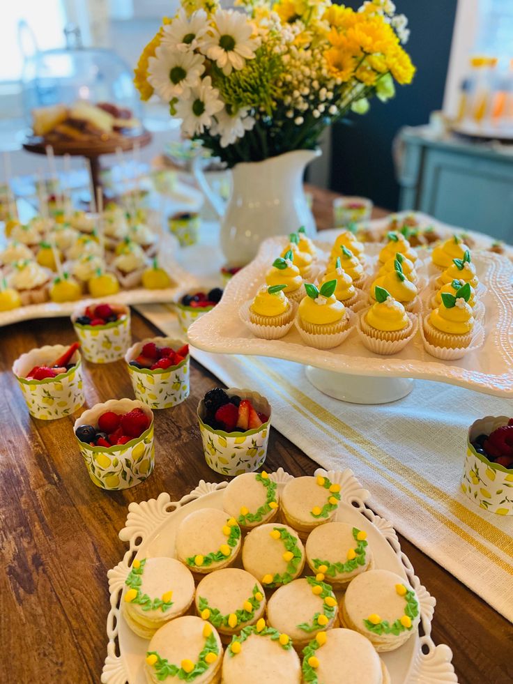 a table topped with lots of cupcakes covered in frosting