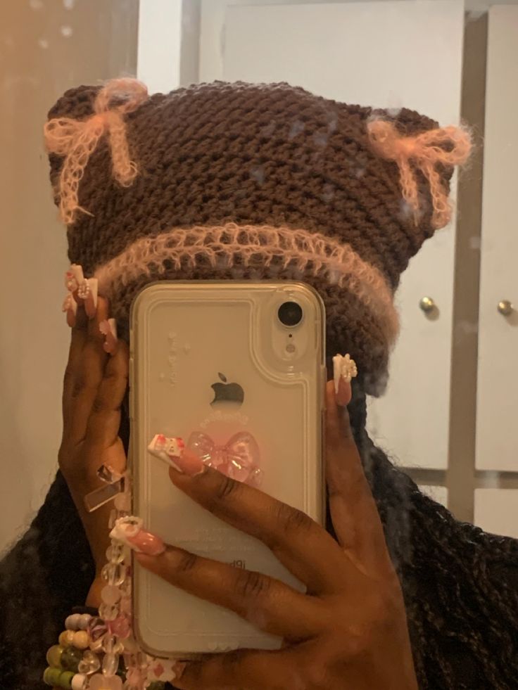 a woman taking a selfie in front of her phone wearing a knitted hat