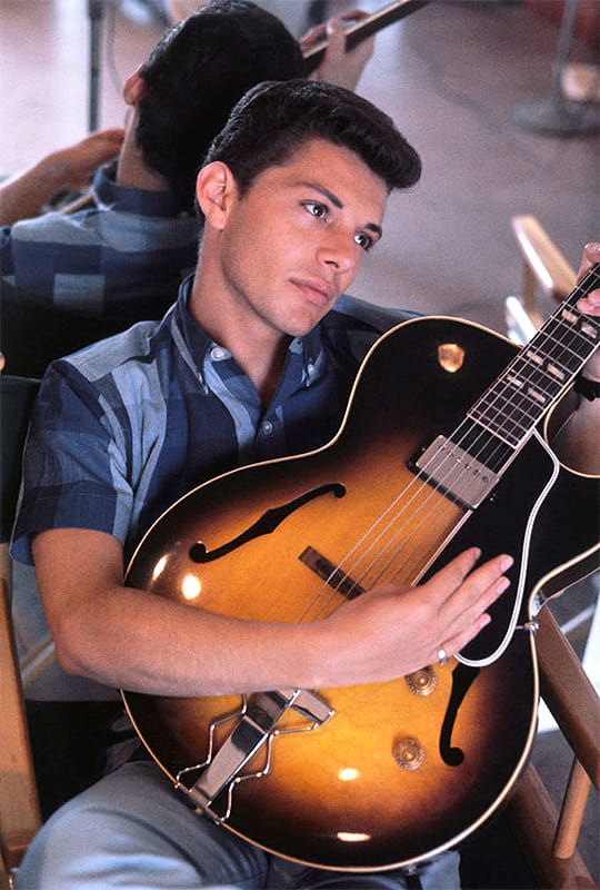 a man sitting in a chair holding a guitar