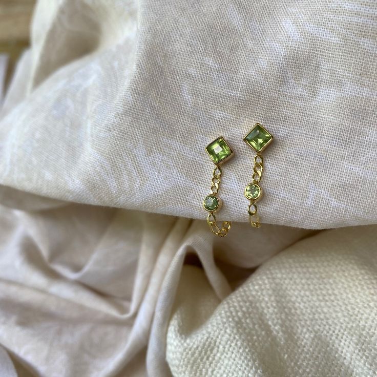 Evie 14K Gold Plated Sterling Silver Green Peridot Studs Never loose your back with these babies! Made with a gorgeous figaro chain these little cuties shine bright by themselves but also pair perfectly with almost any other earring. Made with handpicked green Peridot the top stud is a diamond Peridot leading down to a round shaped Peridot both sitting on the figaro chain which then wraps around the earlobe to the backing. Peridot set in gold is said to develop its full potential as a talisman. * Pretty and petite Studs * High quality 2 micron 14K gold plating to premium jewellery standards * High quality Sterling Silver * Lead & Nickel free * Each Topaz has its own natural sheen so your piece is practically a one of a kind! * Also available in Sterling Silver Peridot is one of the most an Leo Birthstone, Green Stud Earrings, Printed Canvas Bag, Peridot Earrings, Figaro Chain, Earrings Green, Stone Studs, Green Peridot, Green Earrings