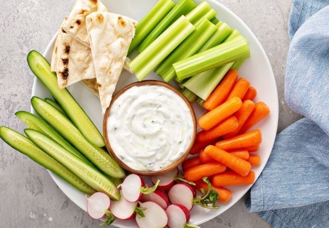 a white plate topped with celery, carrots and pita bread