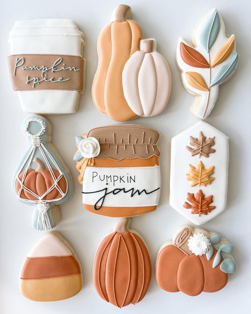 decorated cookies are arranged in the shape of pumpkins and fall leaves on a white surface