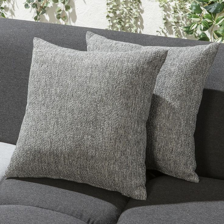 two grey pillows sitting on top of a gray couch