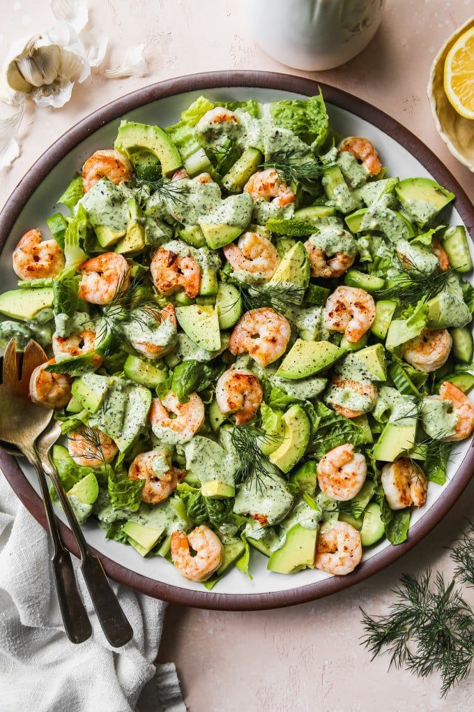 a plate full of shrimp and cucumber salad with lemon wedges on the side