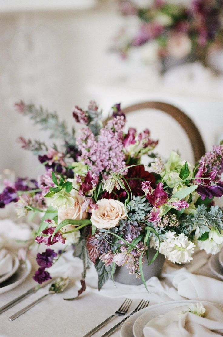 the table is set with white and purple flowers