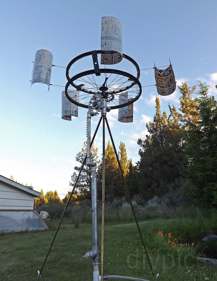 a metal pole with several cups hanging from it's sides in the middle of a yard