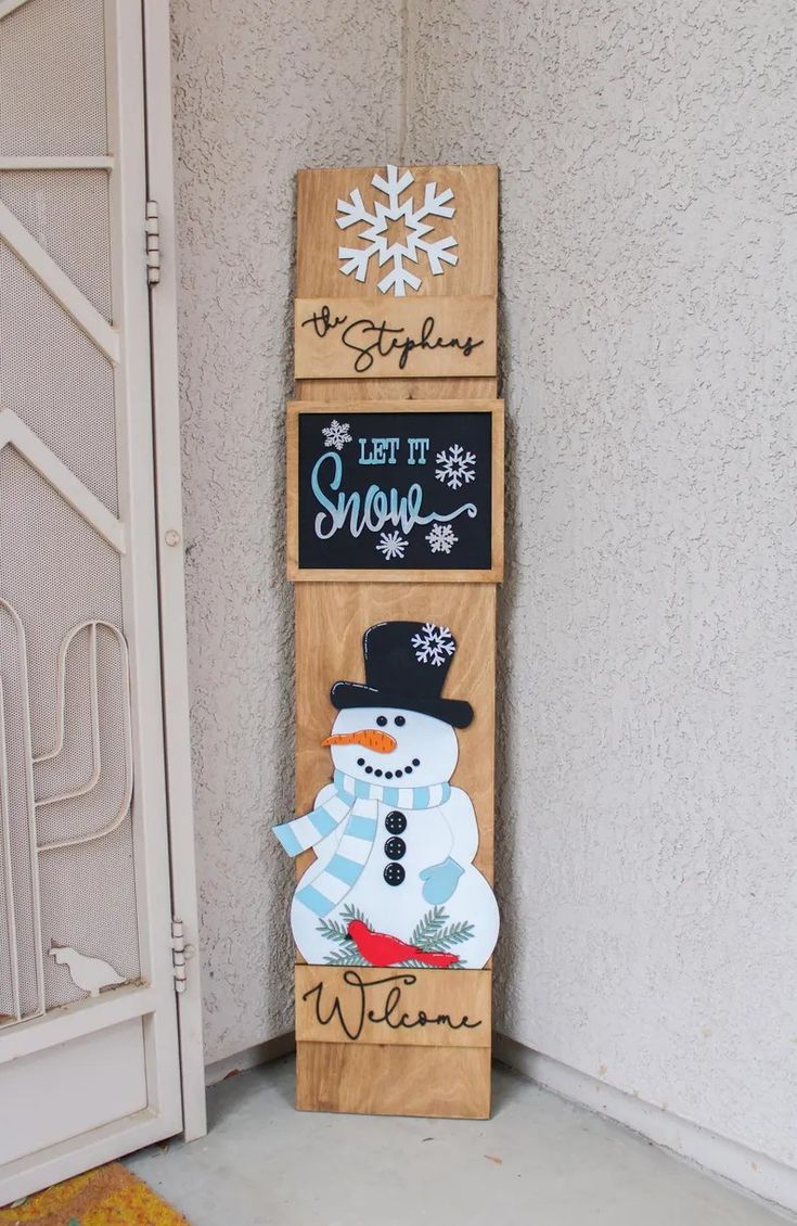 a snowman is standing next to two wooden signs that say let it snow, let it snow