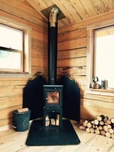 a wood burning stove sitting inside of a wooden cabin