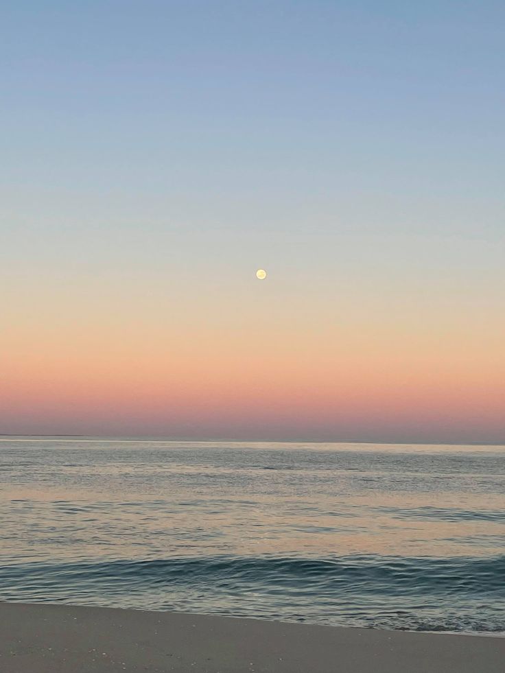 the sun is setting over the ocean and beach