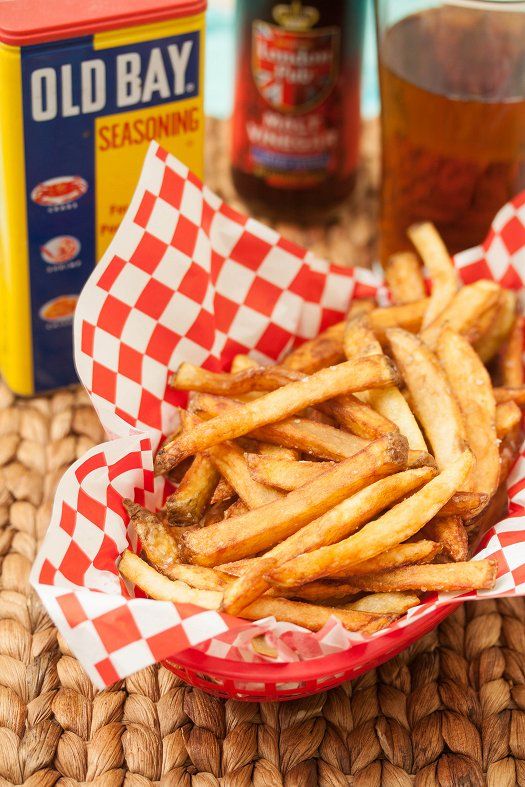 a basket filled with french fries next to a can of beer and some condiments