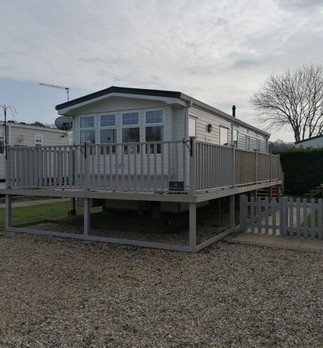 a mobile home sits in the gravel next to a fence