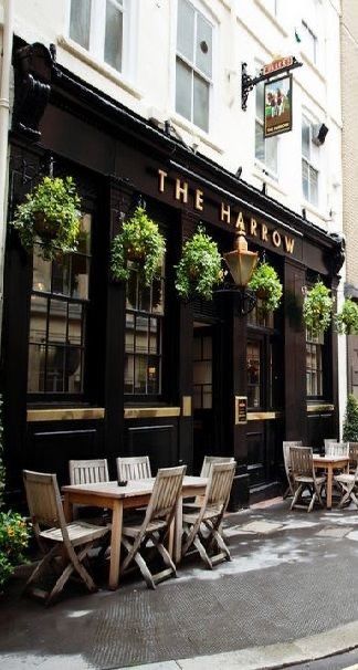 an empty street with tables and chairs in front of a building that says the harrow