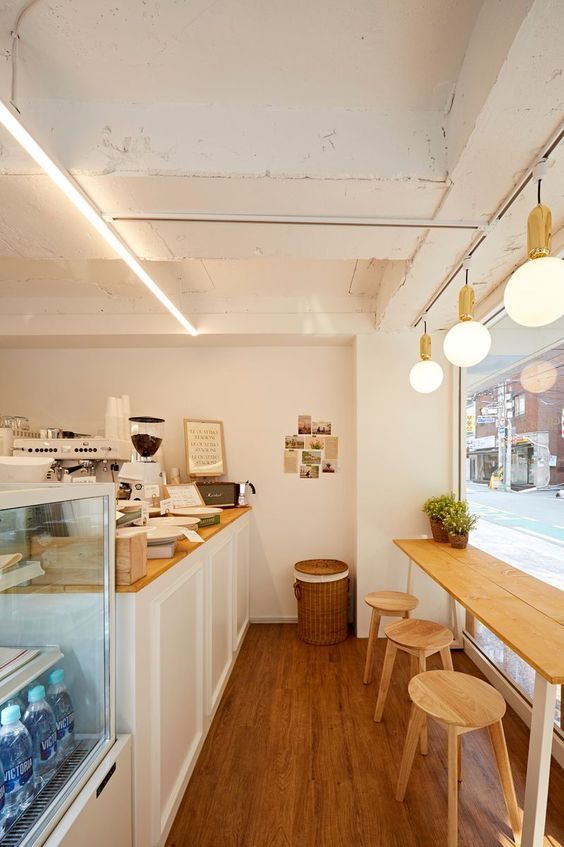 the inside of a small bakery with wooden tables and stools in front of it