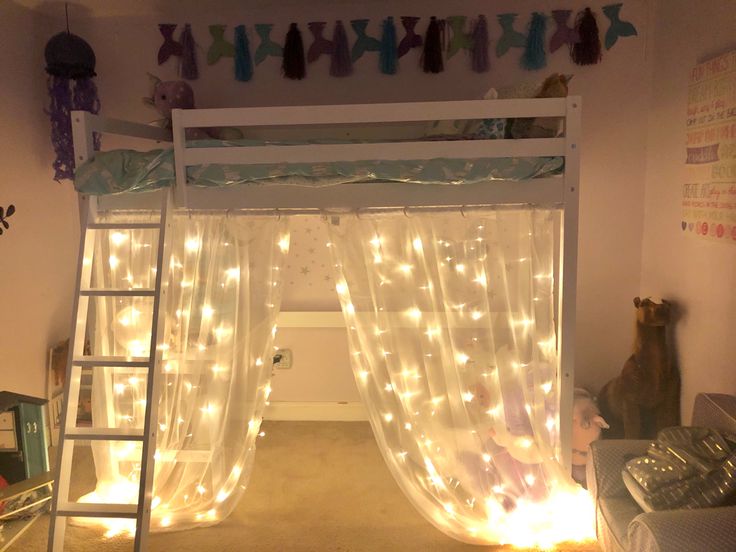 there is a bunk bed with curtains and lights on the bottom level, next to a ladder