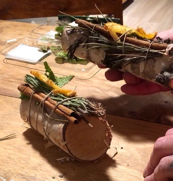 someone is holding up some kind of plant in their hand on a wooden table with other plants growing out of it