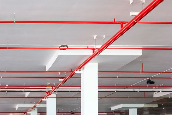 an empty parking garage with red pipes and lights