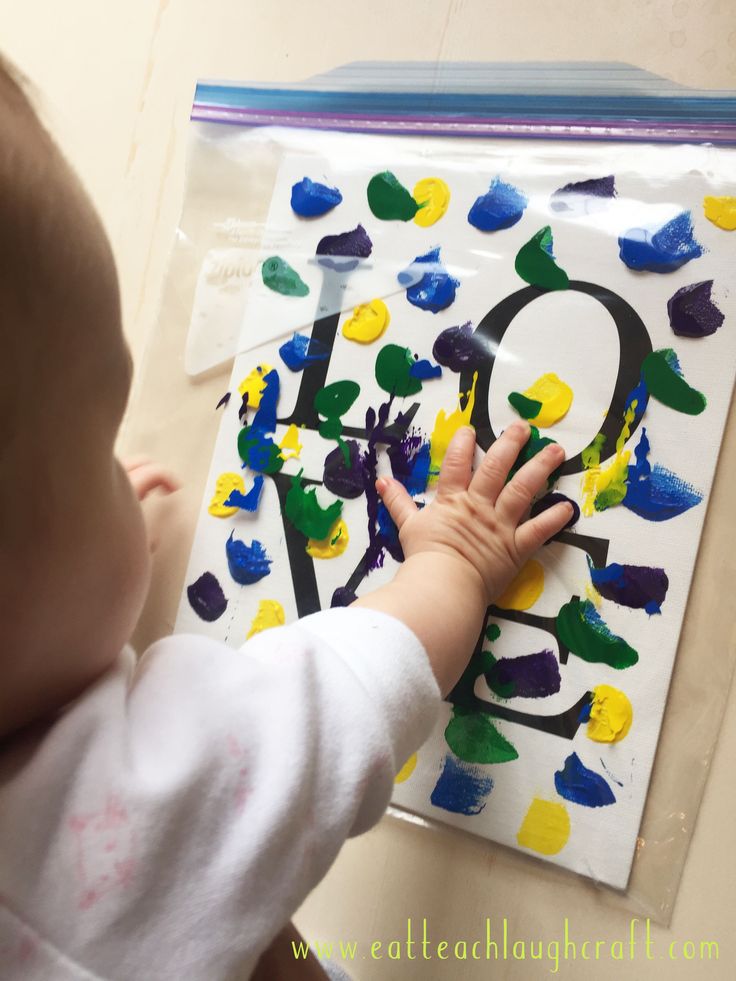 a baby is playing with the letter q made out of handprints on a sheet of paper