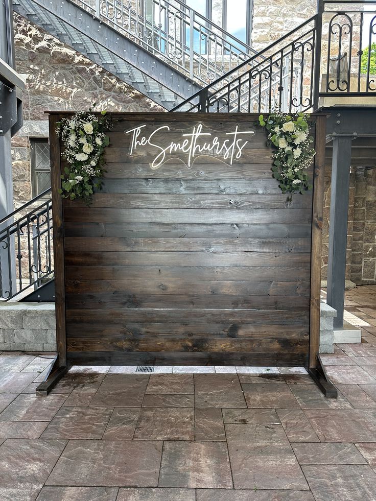 a wooden sign with flowers on it sitting in front of a set of staircases