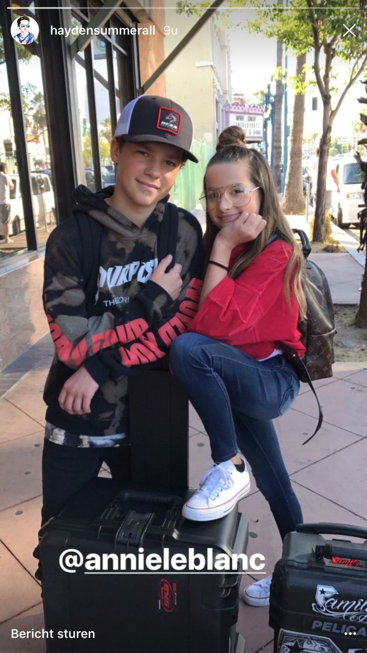 two children sitting on luggage posing for the camera with their arms around each other's shoulders