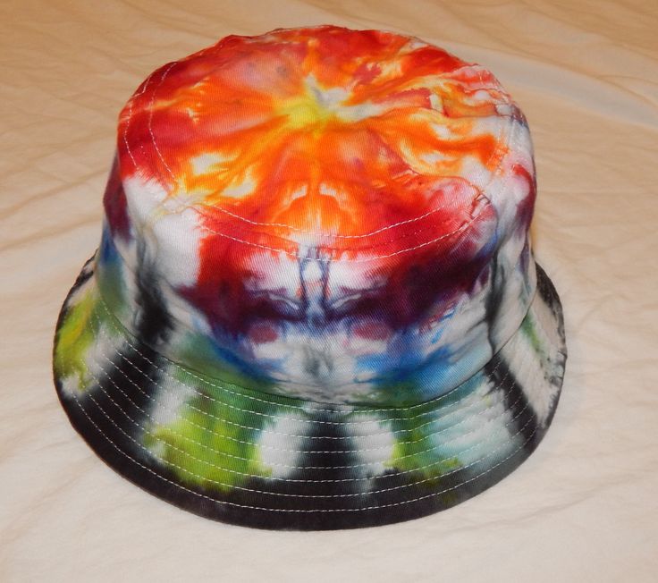 a multicolored tie - dyed bucket hat sits on a bed