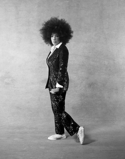 a black and white photo of a woman with an afro in a tuxedo