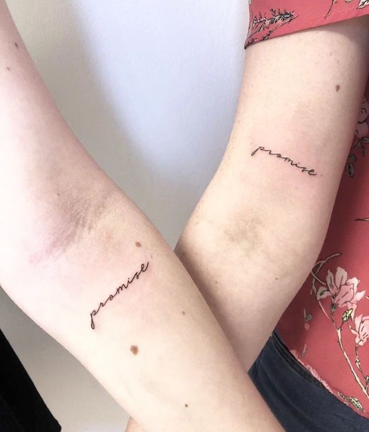 two people with matching tattoos on their arms, one is holding the other's arm