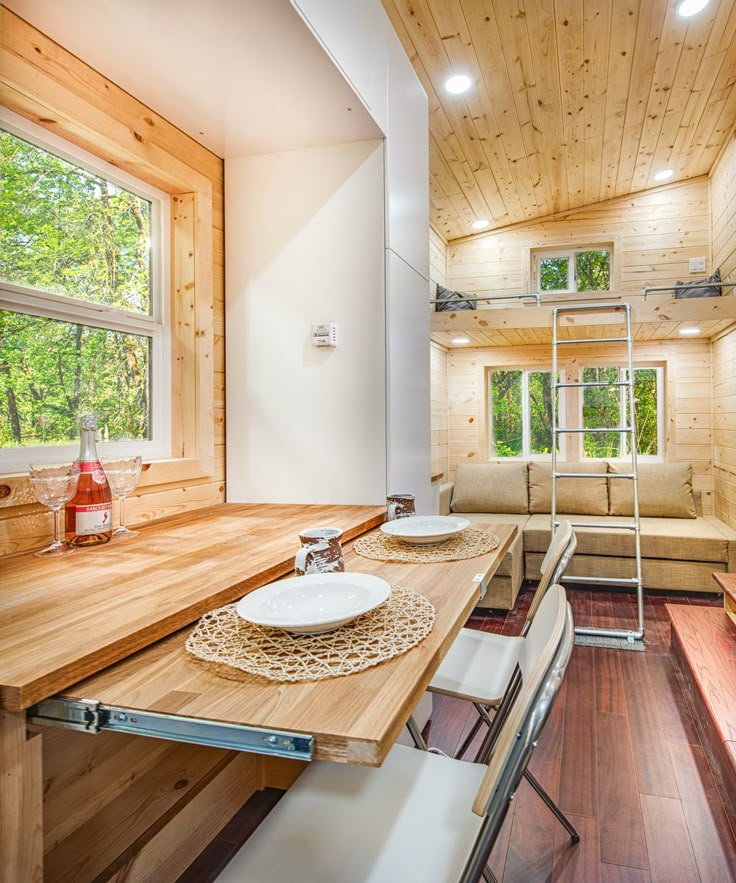 there is a table and chairs in the room with wood walls, windows, and wooden flooring