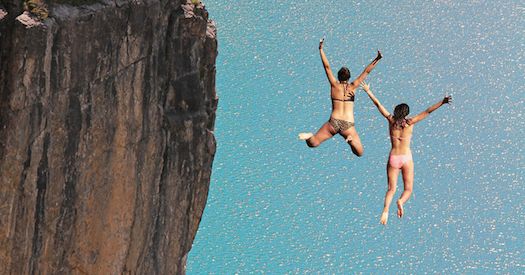 two people jumping off the edge of a cliff into water with an inspirational quote above them