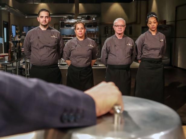 a group of chefs standing in front of a silver pan on top of a counter