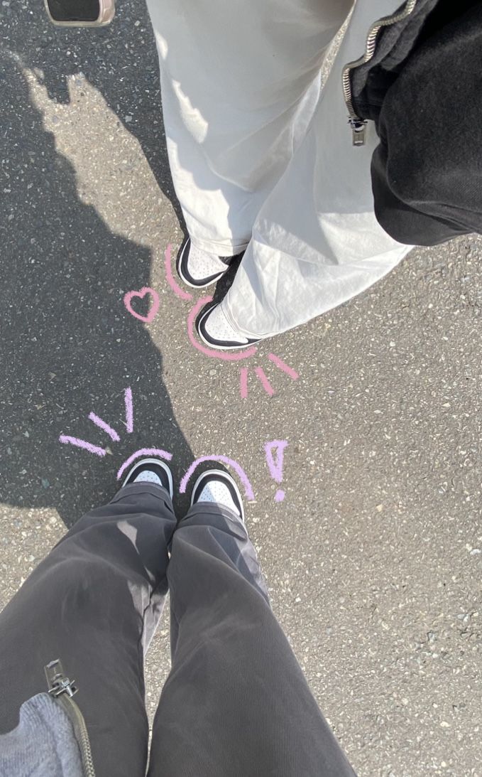 two people standing next to each other with chalk drawings on the ground