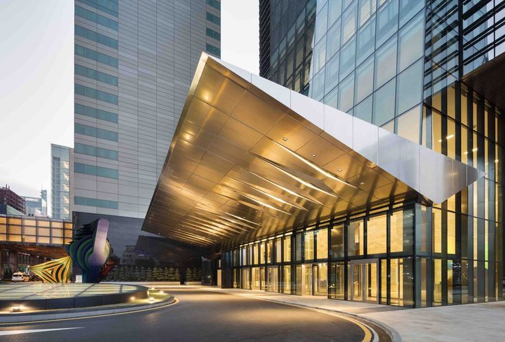 an empty parking lot in front of a building with glass walls and lights on it