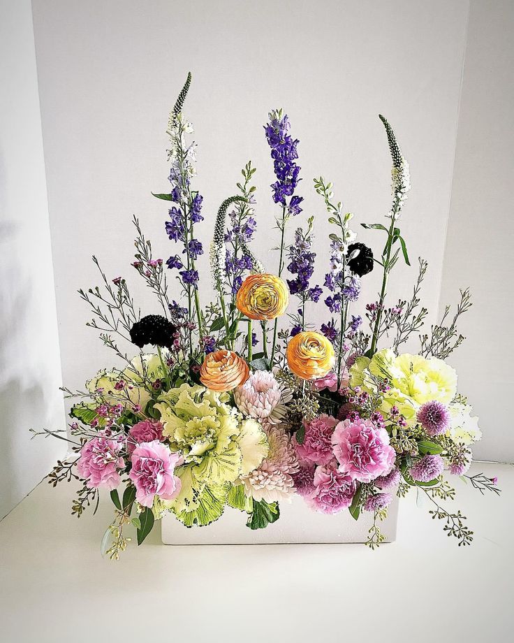 a white vase filled with lots of different colored flowers