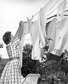 an old black and white photo of a woman drying clothes