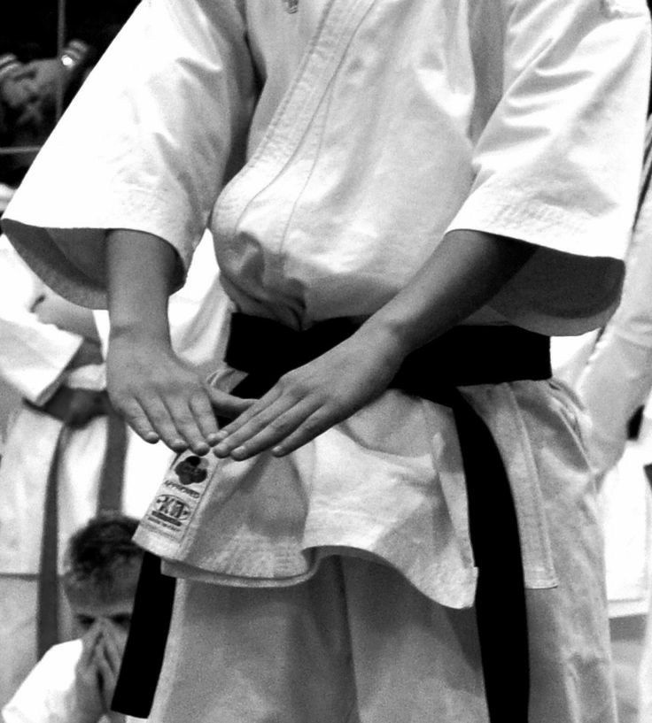 black and white photograph of a person in karate attire with their hands on the belt