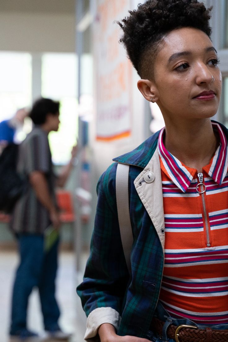 a woman standing in an airport with her hand on her hip and looking off to the side