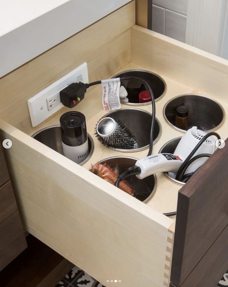 an open drawer with hair dryers and combs in it