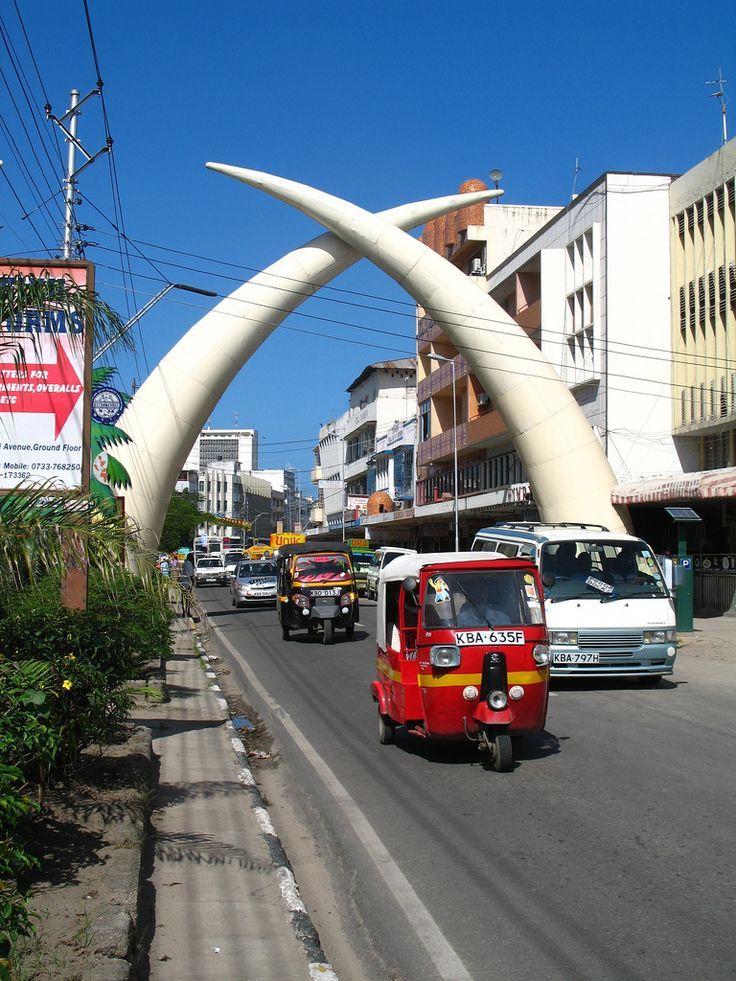 cars driving down the road with large white horns on it's back end and an arch in the middle