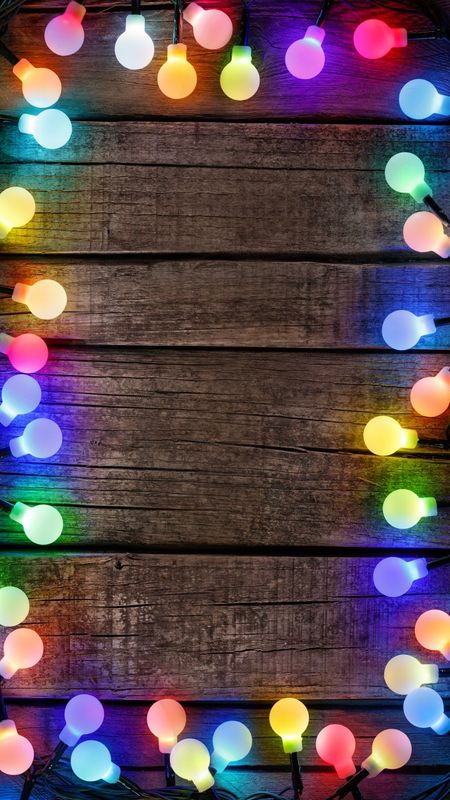 colorful lights are arranged in the shape of a circle on a wooden background with space for text